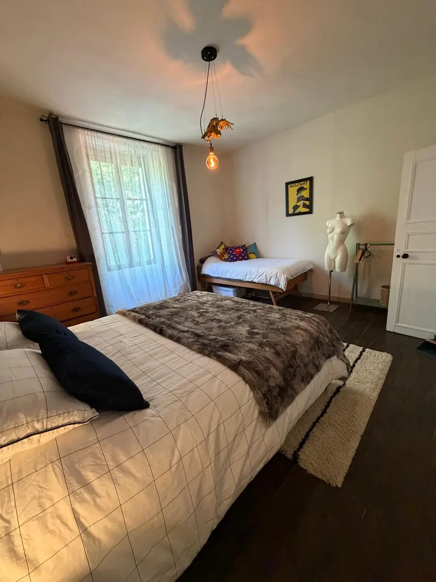 Bedroom One from beside the king bed, looking towards the tall curtained window and the single bed