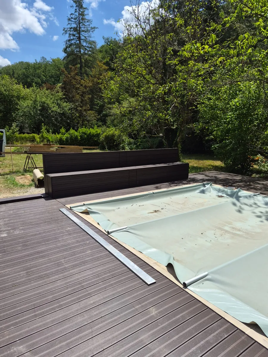 The pool with its cover partly drawn across the water, seen from the timber decking
