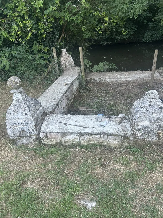 Weathered low stone seats and carved blocks on the grass beside the river