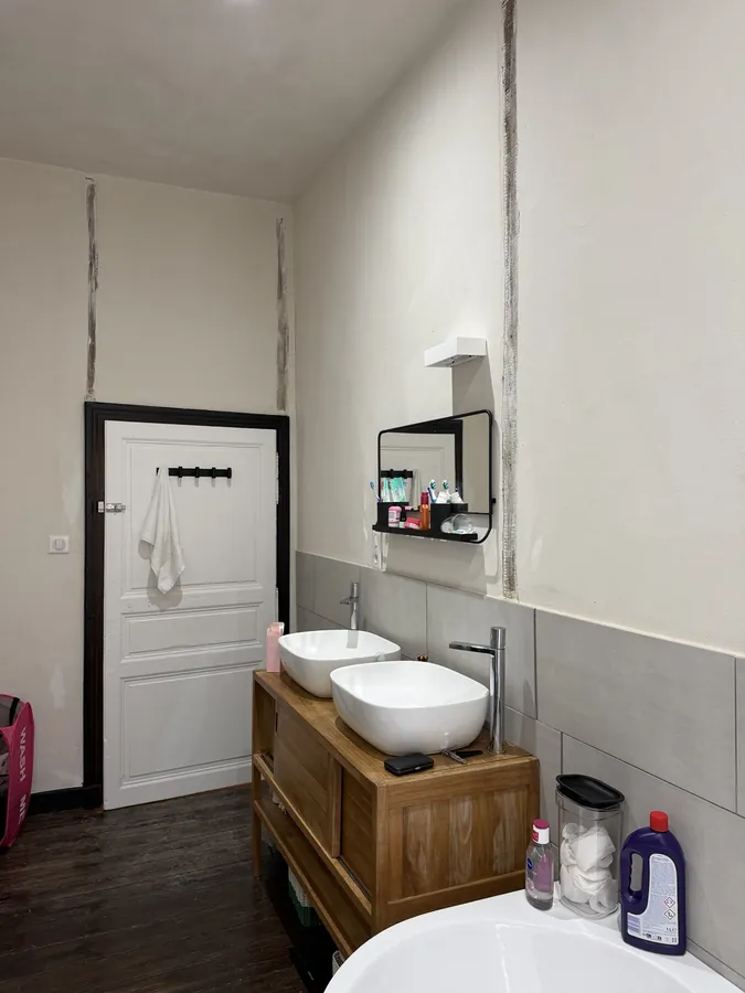 Twin white basins on a wooden vanity unit with a mirror and shelf above