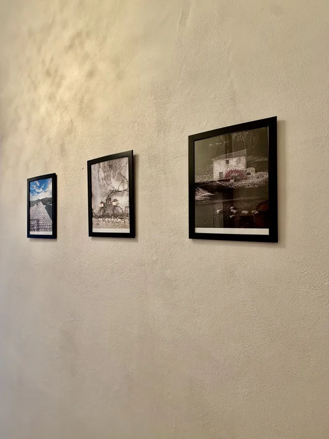 Three framed photographs of Confolens hung in a row along a pale hallway wall