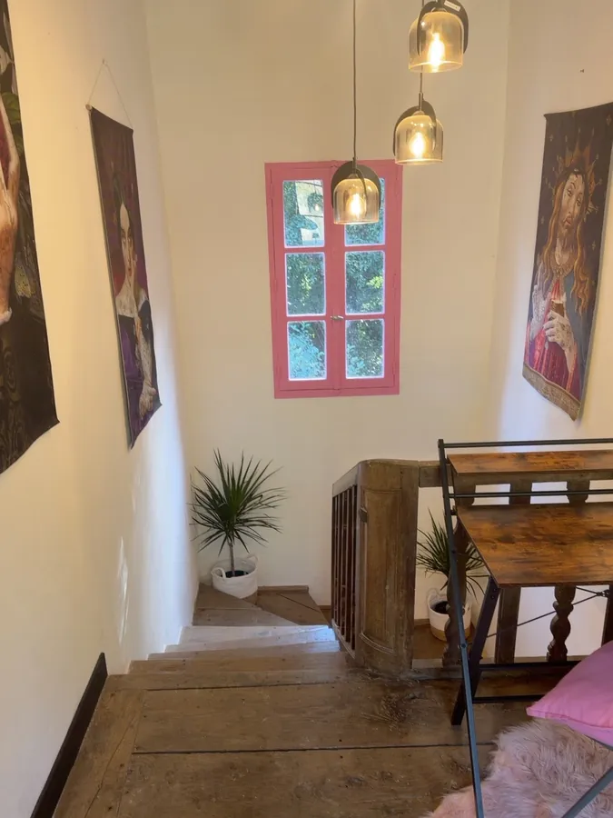 The landing with glass pendant lights, a pink-framed window and framed portraits either side