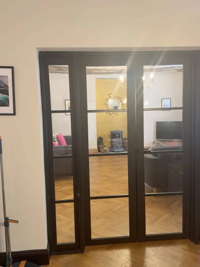 Tall black-framed glazed double doors connecting the lounge to the next room