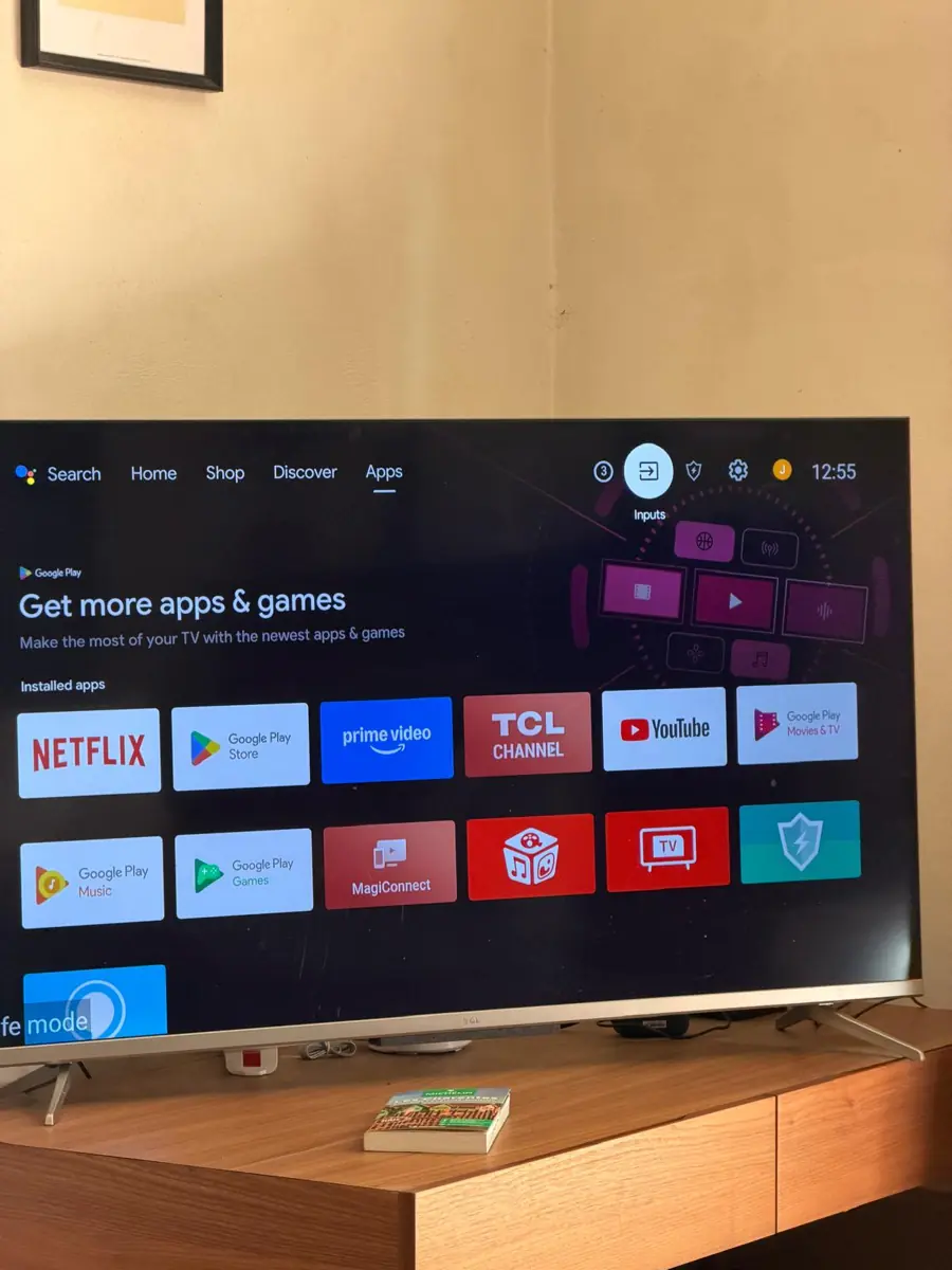 The TV home screen showing rows of apps including Netflix, Prime Video and YouTube, with a row of icons along the top right